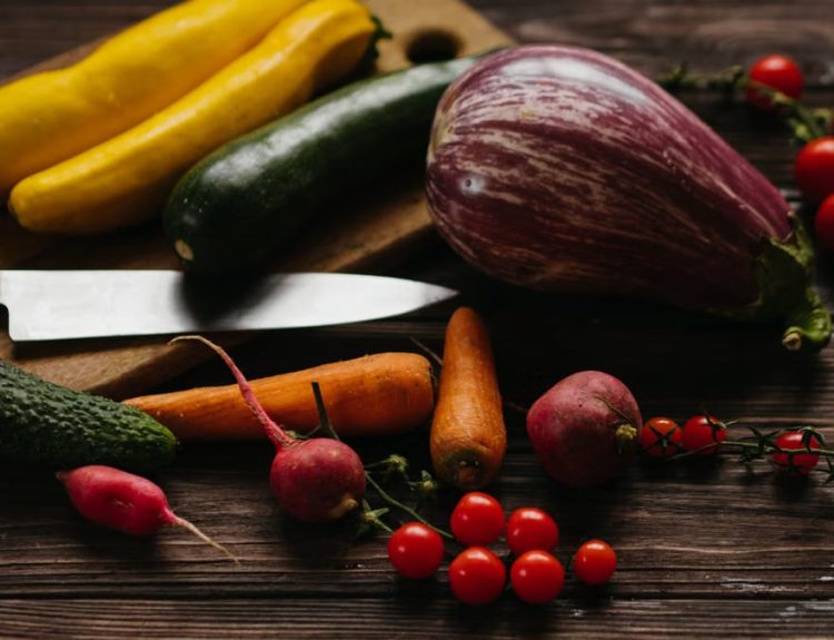 A vibrant assortment of fresh vegetables including zucchini, eggplant, and tomatoes on a wooden board.