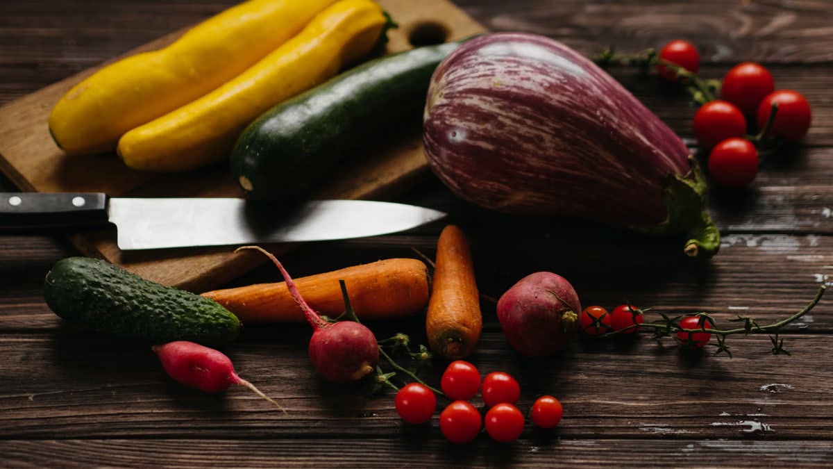 A vibrant assortment of fresh vegetables including zucchini, eggplant, and tomatoes on a wooden board.